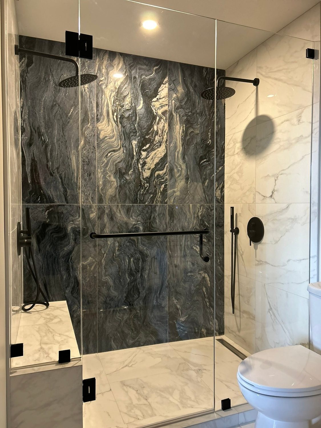 Custom frameless glass shower with dark stone tile by Loyalty Glass
